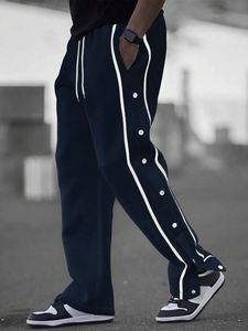 Detail of men's high street joggers showing side snap buttons and white stripes decoration