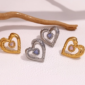 Detail of hollow heart earrings in 18K gold and silver with iridescent opal stones