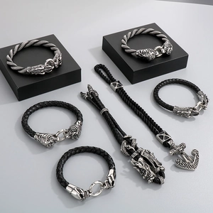 Close-up of vintage dragon head and anchor charms on braided leather bracelets