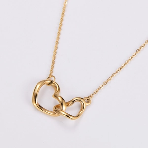 Close-up of golden interlocking double heart pendant on a thin O-chain necklace