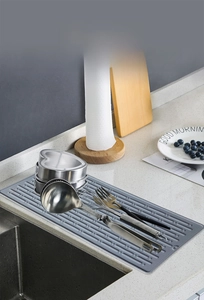 Detail of grey silicone drying mat with raised ridges showing kitchen utensils drainage