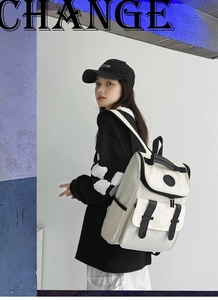 Side view of black and white color-block backpack with flap buckle on model in studio