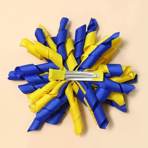 Handmade blue and yellow spiral ribbon hair clip for girls on peach background