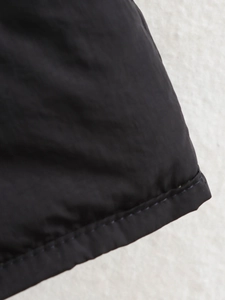 Detailed close-up of double-stitched hem on black quilted casual jacket fabric
