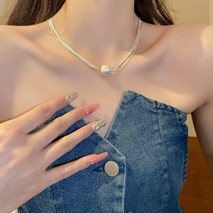 Dettaglio di collane d'argento a più strati con una grande perla centrale da donna