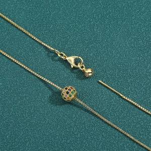 Elegant gold box chain necklace with multi-color zircon stone pendant on green background