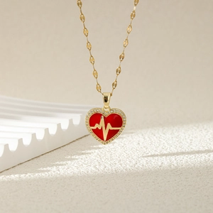 Elegant heart pendant necklace with red enamel and gold heartbeat line on beige background