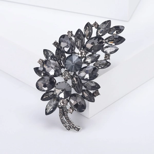 Elegant silver leaf brooch with smokey grey crystals on a minimalist display stand