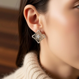 Macro shot of silver hollow star earrings with zircons worn by a model