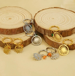 Détail macro de boucles d'oreilles soleil et œil en acier inoxydable sur bois naturel