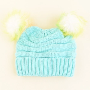 Detail of blue knitted baby hat showing ribbed edges and yellow gradient pom-poms