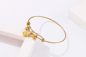Close-up of golden stainless steel bracelet featuring a guitar pendant and round beads