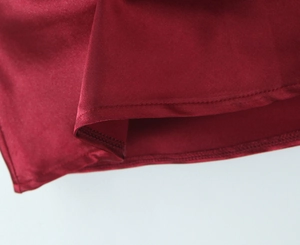 Gros plan détaillé des coutures fines sur l'ourlet du vêtement en satin rouge foncé