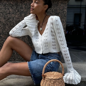 Detailed view of white hollow-out knit texture with elegant flare cuffs and V-neckline
