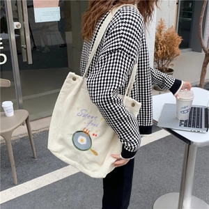 Détail du sac cabas en velours côtelé écru avec broderie colorée et boucle métallique