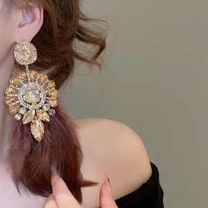 Détail de boucles d'oreilles en zircon champagne avec plumes brunes et design floral vintage