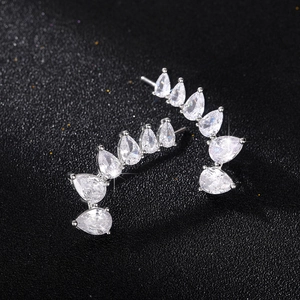 Macro detail of silver ear climber with graduated pear-cut cubic zirconia on black background