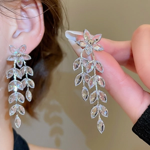 Detail of silver flower and wheat ear tassel earrings with sparkling rhinestones on model
