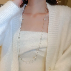Close-up of gold plated long necklace with irregular pearls and tassels on a model
