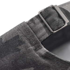 Macro view of adjustable metal buckle and vintage camo twill texture on baseball cap