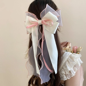 Rear view of an elegant large off-white lace bow hair clip worn with long flowing ribbons