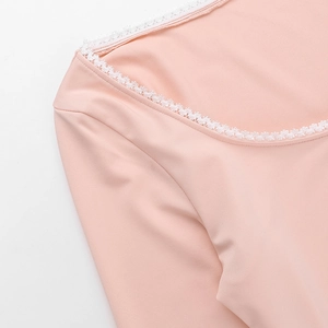 Detailed view of pink long-sleeve top with delicate white lace trim and bow on square neck