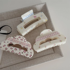 Floral and checkered hair claw clips set with bow patterns on creamy white acrylic
