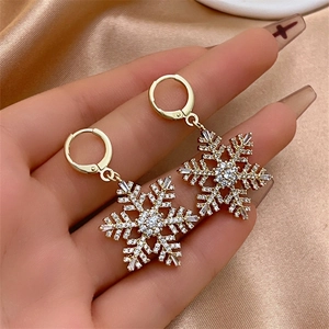 Detailed close-up of sparkling gold snowflake tassel earrings with white zircon accents