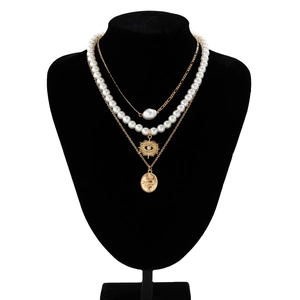 Detail of layered gold necklaces with sun and snake pendants on black velvet bust