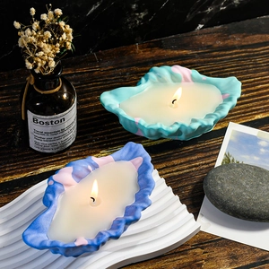 Brandende schelpvormige geurkaarsen met marmerpatroon op een decoratieve houten tafel