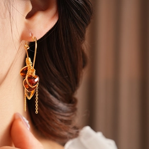 Detail of 18K gold-plated heart earring with amber glass and vintage tassel fringe