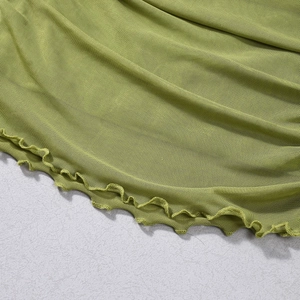 Gros plan sur le tissu en maille vert herbe avec des volants et des bords ondulés fins