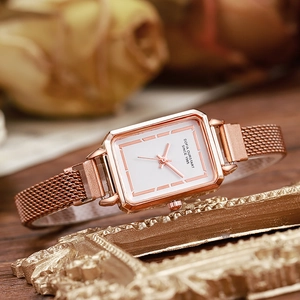 Detailed macro view of the rectangular rose gold case and Milanese mesh strap on watch