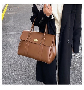 Brown leather large tote bag with gold metal twist lock shown in a professional setting