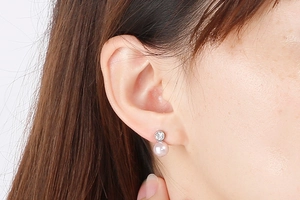 Close-up of elegant pink pearl drop earring with silver diamond setting on female model