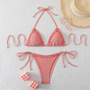 Flat lay of red and white striped ruffled bikini set with beach vacation accessories