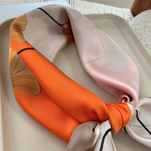Detail view of orange and beige silk scarf with elegant ginkgo leaf pattern