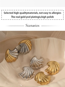 Detail of PVD gold plated shell earrings with high polish finish in a ceramic dish