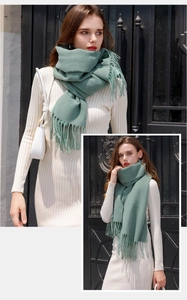 Detail of green pashmina scarf with long fringes shown on model for soft texture