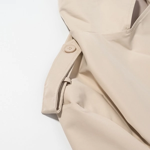 Dettaglio macro della spalla di un trench beige con spallina e cuciture del bottone