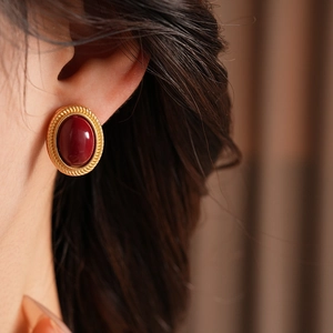Close-up of vintage gold oval red gemstone stud earrings worn by a female model
