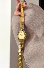 Detail of GEDI gold water-drop luxury watch with diamond bezel and metallic chain strap