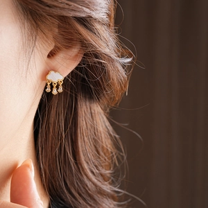 Macro view of cloud and raindrop stud earrings with zircon inlay on a model ear