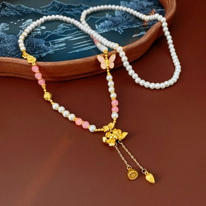 Detailed close-up of lotus flower and butterfly pendant with tassels on pearl necklace
