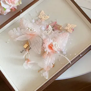Detail of pink gauze flower hair clips with golden butterflies and pearl tassels