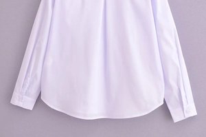 Detail view of the smooth hem and premium cotton fabric on white long sleeve blouse