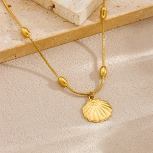 Gold plated stainless steel scallop pendant necklace with oval bead chain on a stone