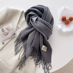 Flat lay of charcoal grey cashmere scarf with fringe details and woven label