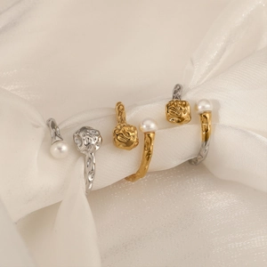 Bague ouverte organique irrégulière avec perle sur un tissu de soie blanc drapé