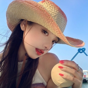 Detail of gradient straw cowboy hat with chin strap against a clear blue sky background